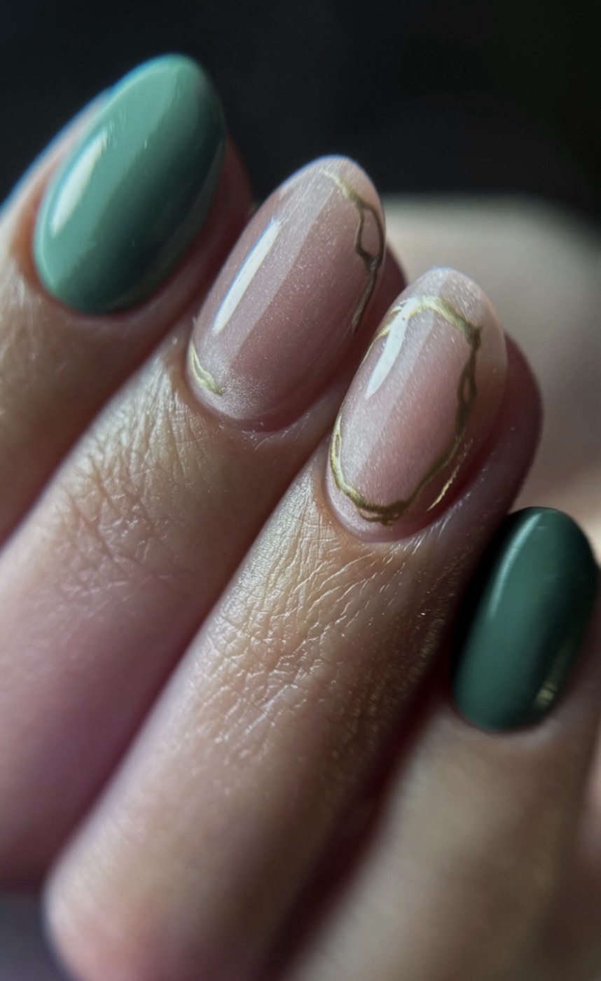 Manicura verde esmeralda con líneas doradas